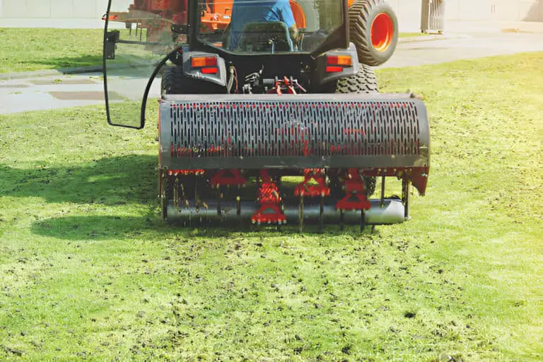 gardener operating soil aeration machine on grass lawn