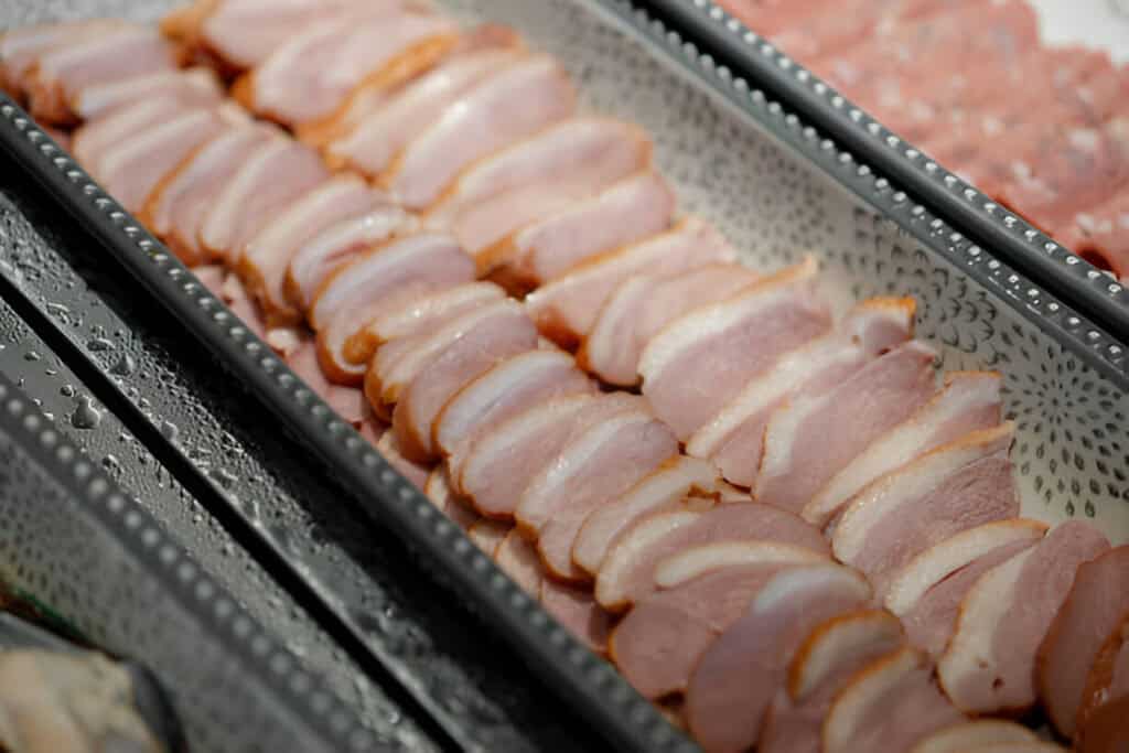 slices of smoked duck arranged on a ceramic plate buffet