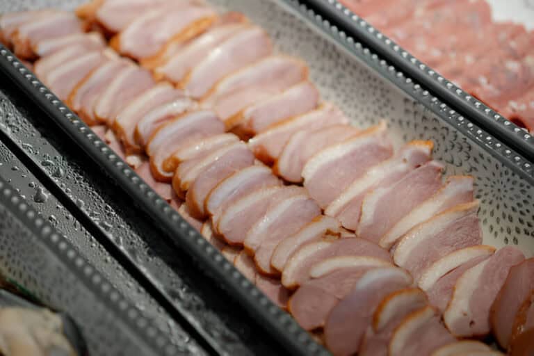 slices of smoked duck arranged on a ceramic plate buffet